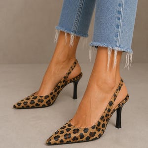 Op de afbeelding: Slingback pumps met luipaardprint met spitse neuzen en zwarte hakken. De schoenen worden gecombineerd met een blauwe jeans met rafelige zomen. De hakken zijn ongeveer 7,6 cm hoog.