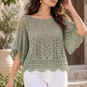 May include: A sage green crochet top featuring an intricate geometric pattern, wide bell sleeves, and a scalloped hemline. The garment is crafted with a delicate openwork design, showcasing a boat neckline and a loose, flowing silhouette.