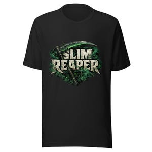 Puede incluir: Una camiseta negra de manga corta con un estampado gráfico en el pecho. El diseño muestra el texto SLIM REAPER en una fuente de piedra desgastada, detrás de una guadaña verde brillante rodeada de humo y niebla verde que se arremolina.