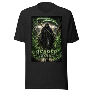 Puede incluir: Una camiseta negra de manga corta con un estampado gráfico de una figura encapuchada que sostiene una guadaña verde brillante. La figura se encuentra en un estadio con luces brillantes al fondo. El texto REAPER SEASON está impreso en verde.
