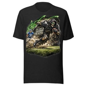Puede incluir: Una camiseta negra con un gráfico de un esqueleto encapuchado con armadura oscura corriendo con un balón de fútbol americano en un campo. El esqueleto tiene ojos verdes brillantes y es perseguido por un jugador con camiseta azul. Texto: YOU CAN'T GUARD DEATH.