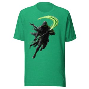 Puede incluir: Camiseta verde con una ilustración digital de una figura encapuchada empuñando una guadaña verde brillante. La figura negra, con capucha y túnica, se alza sobre un fondo verde. El diseño tiene un tema de fantasía o gótico.