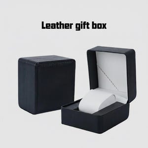 May include: Black leather gift box, open to reveal a white watch holder. The box is square with a hinged lid and a white interior. The text "Leather gift box" is at the top.