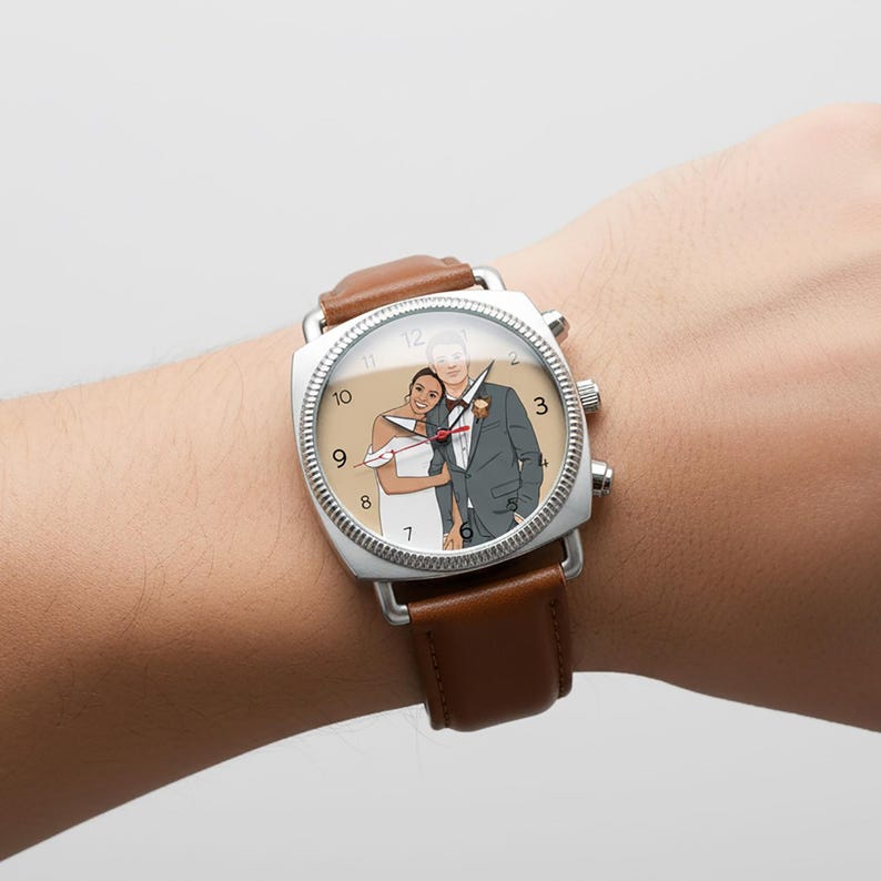 May include: A square-faced wristwatch with a brown leather strap. The watch face displays a cartoon illustration of a couple in wedding attire. The watch has a silver bezel and a brown leather strap.