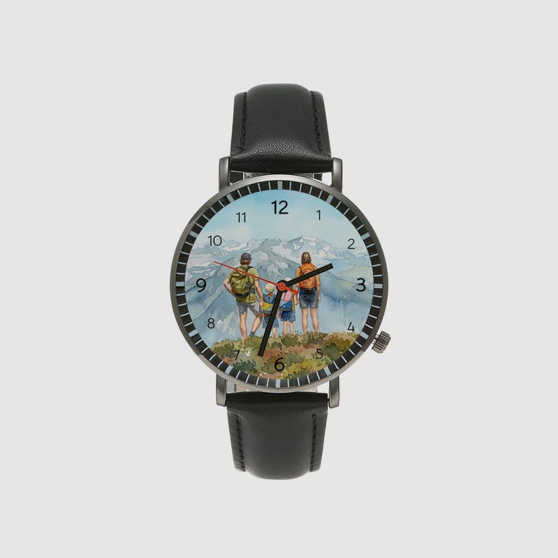 May include: A black wristwatch with a leather band. The watch face features a watercolor painting of a family hiking in the mountains. The watch has a black bezel and silver hands. The watch case is approximately 1.5 inches in diameter.