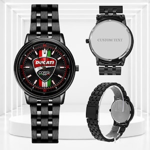 Könnte beinhalten: Eine schwarze Armbanduhr aus Metall mit dem Ducati Corse Logo auf dem Zifferblatt und vertikalen Streifen in Rot, Weiß und Grün. Die Uhr hat ein passendes schwarzes Gliederarmband. Eine Ansicht zeigt den Gehäuseboden mit dem Text CUSTOM TEXT.