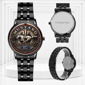 Könnte beinhalten: Eine schwarze Metallarmbanduhr mit einem Ford Mustang 40th Anniversary Zifferblatt, einem silbernen Pferdeemblem, dem Text MUSTANG 40TH ANNIVERSARY, 1964-2004 und dem Ford-Logo. Die Uhr hat ein schwarzes Gliederarmband und ein Gehäuse mit CUSTOM TEXT.