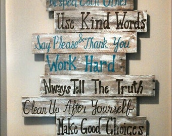 May include: A rustic wooden sign with the words "Family Rules" written in brown paint. The sign is made up of several planks of wood, each with a different rule written on it in black and blue paint. The rules are: "Respect Each Other", "Use Kind Words", "Say Please & Thank You", "Work Hard", "Always Tell The Truth", "Clean Up After Yourself", "Make Good Choices", and "Say I Love You & I'm Sorry".