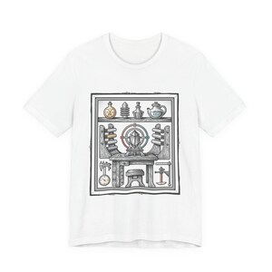 May include: White t-shirt featuring a detailed illustration of a workshop scene. The design includes a table with tools, a central crystal, and various bottles and objects on shelves above. The artwork is in a vintage, hand-drawn style.