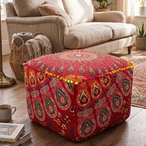 Peut inclure: Un pouf carré rouge orné d'un motif cachemire détaillé dans des tons de bleu, vert et jaune. Le dessus présente un motif circulaire et les bords sont ornés de pompons colorés. Cette pièce décorative ajoute une touche vibrante à tout espace de vie.