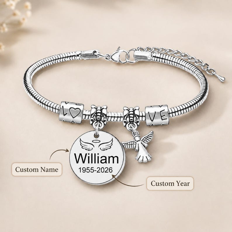 May include: Silver charm bracelet with a snake chain. The bracelet includes charms spelling "LOVE", a heart, and an angel pendant. A round charm with the name "William" and the years "1955-2026" is also included.
