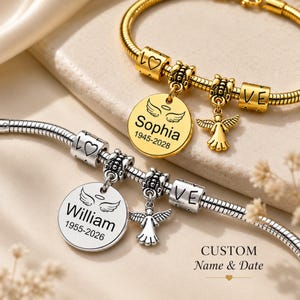 May include: Two personalised charm bracelets. One gold-toned with a round charm engraved with "Sophia" and dates, and a small angel charm. The other is silver-toned with a similar charm engraved with "William" and dates, and an angel charm.