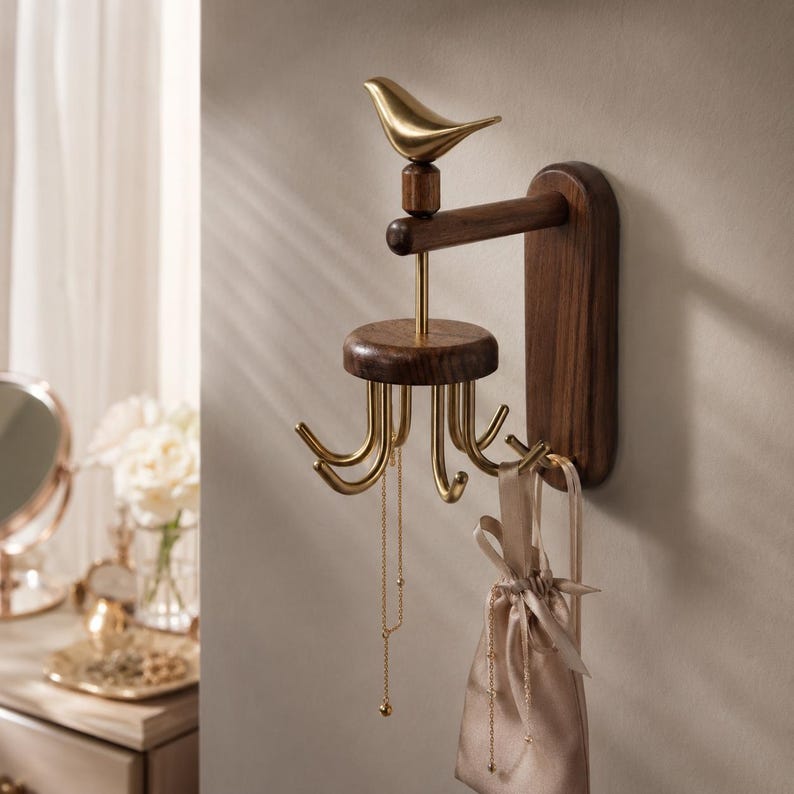 May include: A wall-mounted jewelry organizer featuring a dark wood vertical base and horizontal arm. A gold-toned metal bird sits atop the arm, connected to a rotating circular wood platform with six curved gold hooks for hanging necklaces and pouches.