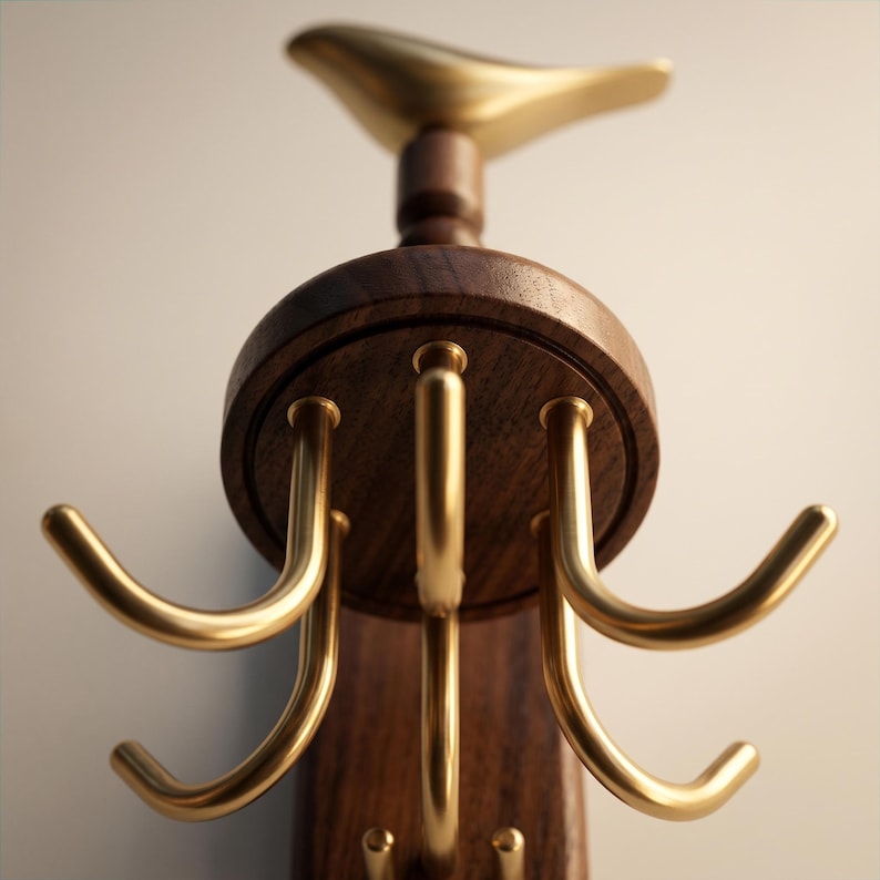 May include: A wall-mounted organizer featuring a dark brown wooden base and a circular wooden mount. The top is adorned with a smooth, gold-toned metal bird figure. Below, six curved, gold-toned metal hooks extend outward for hanging items.
