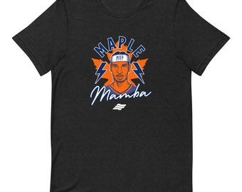May include: A charcoal grey short-sleeve t-shirt featuring a graphic of a person wearing an MVP headband. The design includes orange maple leaves, blue lightning bolts, and the text "MAPLE" and "Mamba" in blue and white script.