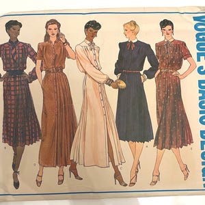 May include: Vintage Vogue's Basic Design sewing pattern featuring five illustrated women's dresses. The dresses include a plaid two-piece set, a button-down dress, a long-sleeved dress, and a short-sleeved dress. The pattern is labeled "2208".