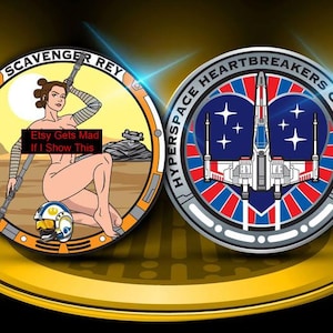 Puede incluir: Dos monedas redondas de metal con borde dorado. Una moneda presenta una figura de dibujos animados desnuda con el texto "Scavenger Rey". La otra moneda tiene un diseño de nave espacial con el texto "Hyperspace Heartbreakers Collection".