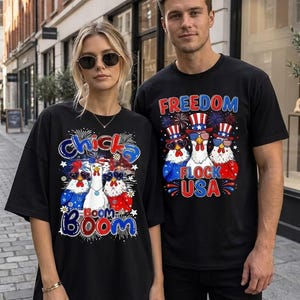 May include: Two black t-shirts featuring graphic prints of chickens wearing patriotic top hats and star-spangled sunglasses. The left shirt displays the text Chicka Boom, while the right shirt features the text Freedom Flock USA with fireworks.