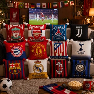 K&ouml;nnte beinhalten: Eine Sammlung von zw&ouml;lf quadratischen Dekokissen mit den Logos und Farben verschiedener Profifu&szlig;ballmannschaften, darunter Liverpool, Arsenal, Paris Saint-Germain, Juventus, Bayern M&uuml;nchen, Manchester United, Atletico Madrid, Tottenham, Barcelona, Real Madrid, AC Milan und Inter Mailand.
