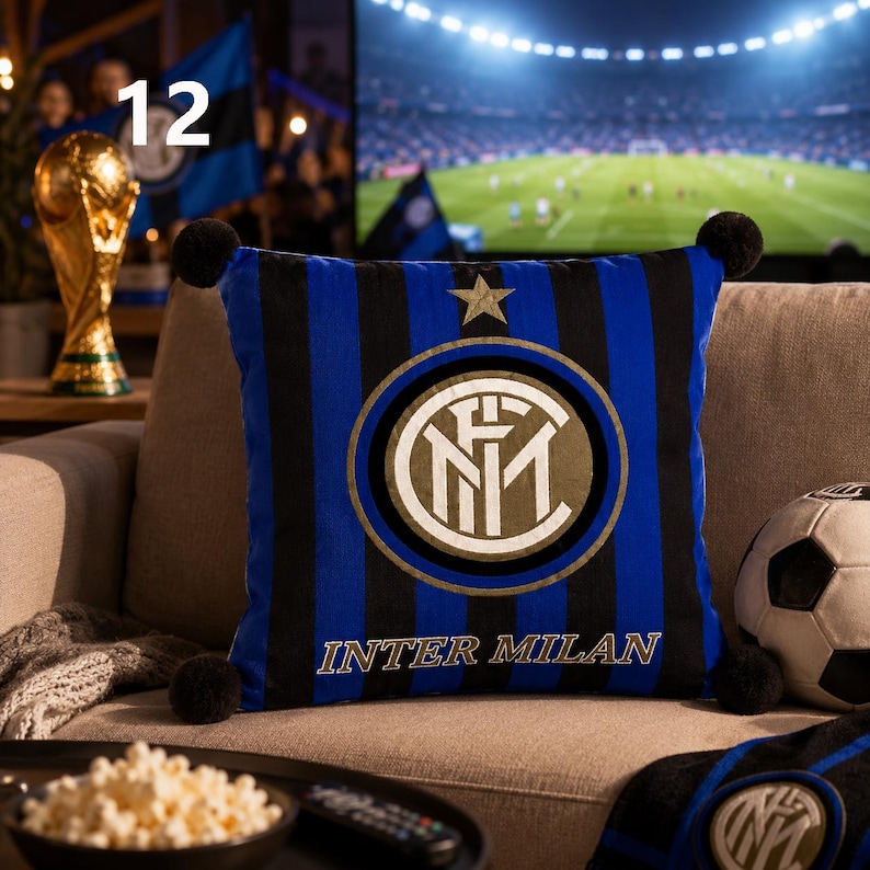 K&ouml;nnte beinhalten: Ein quadratisches Zierkissen mit vertikalen schwarzen und blauen Streifen, einem goldenen Stern und dem kreisf&ouml;rmigen Inter-Mailand-Logo mit dem Text INTER MILAN. Das Kissen hat an allen vier Ecken schwarze Bommeln und besteht aus Stoff.
