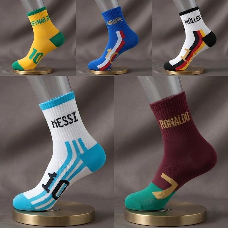 Peut inclure: Cinq paires de chaussettes de sport expos&eacute;es. Chaque chaussette pr&eacute;sente une combinaison de couleurs diff&eacute;rente et le nom d'un joueur de football. Les chaussettes sont jaunes, bleues, blanches, bordeaux et blanches. Chaque chaussette a un design diff&eacute;rent.