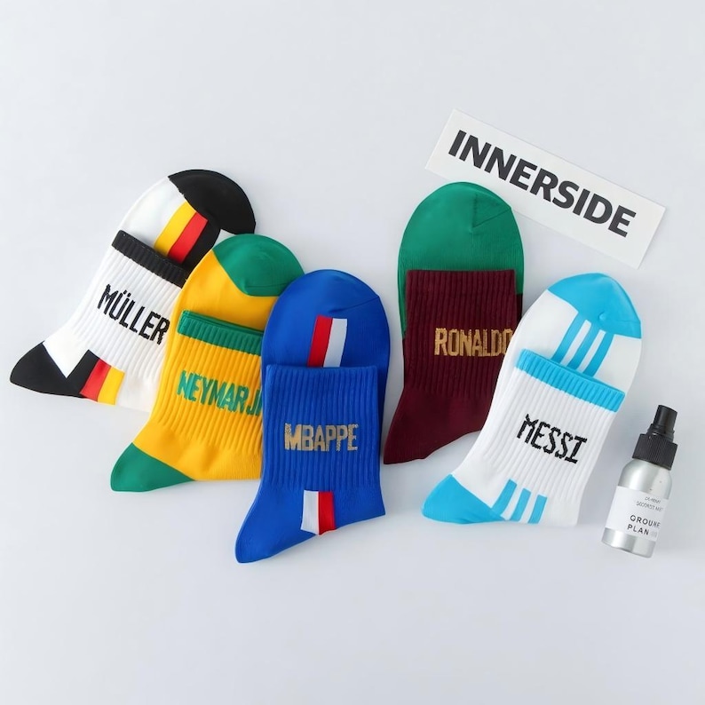 Peut inclure: Une collection de chaussettes de sport color&eacute;es avec les noms "MULLER", "NEYMAR", "MBAPPE", "RONALDO" et "MESSI" en lettres dor&eacute;es. Chaque chaussette a un code couleur unique, avec du blanc, noir, jaune, vert, bleu et bordeaux. Le mot "INNERSIDE" est imprim&eacute; sur un rectangle blanc.