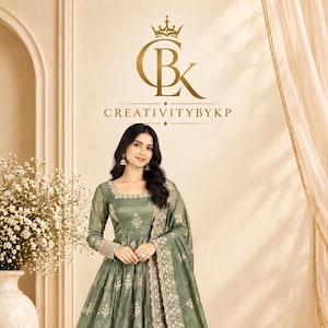 Puede incluir: Un vestido largo hasta el suelo de color verde salvia con mangas largas y escote cuadrado. El vestido presenta un intrincado bordado floral blanco en el corpiño y la falda, con un borde denso y detallado en el dobladillo y un dupatta a juego.