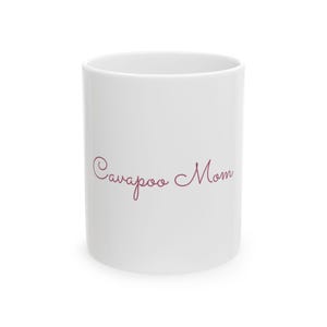 May include: White ceramic mug with the text "Cavapoo Mom" in a cursive, burgundy font. The mug is cylindrical and has a simple, clean design, suitable for hot beverages.