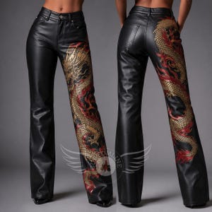 Op de afbeelding: Zwarte broek met een hoge taille, knoopsluiting en riemlussen. De broekspijpen zijn versierd met een grote, gedetailleerde goudkleurige en rode drakenafbeelding die om de zijkant loopt, van de heup tot aan de zoom van de broekspijp.