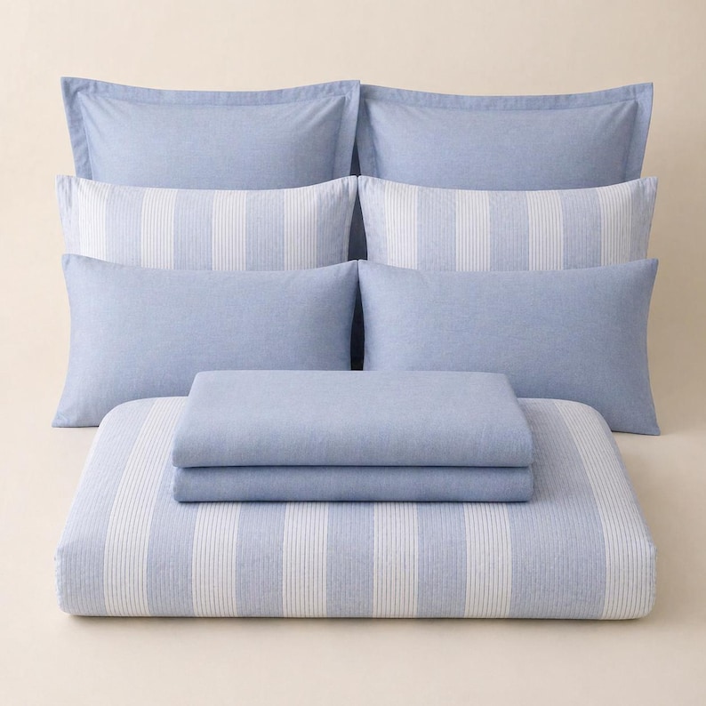 May include: A light blue and white striped bedding set. The set includes several pillowcases, a duvet cover, and a fitted sheet. The pillowcases are solid light blue, while the duvet cover and fitted sheet have vertical white stripes.