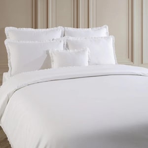 May include: A white bedding set featuring a duvet cover and several pillows. The pillows and duvet cover have ruffled edges. The bedding is arranged on a bed against a neutral-toned wall.