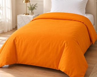 May include: A solid orange duvet cover draped over a bed with a white pillow. The bedding features a smooth, matte texture and covers the mattress completely, extending down to the floor on the sides of the bed frame.
