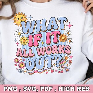 May include: A white sweatshirt featuring a graphic print with the text "WHAT IF IT ALL WORKS OUT?" in blue and pink bubble letters. The design includes a yellow sun, colorful flowers, small mushrooms, cherries, a strawberry, and a rainbow.