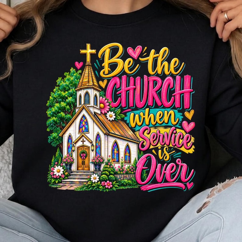 Pode incluir: Uma camisola preta com um gr&aacute;fico colorido de uma igreja com torre, vitrais e flores. O texto diz Be the CHURCH when Service is Over em letras amarelas e cor-de-rosa, decorado com pequenos cora&ccedil;&otilde;es &agrave; volta do desenho.
