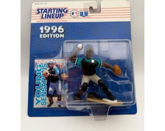 May include: A 1996 Starting Lineup sports superstar collectible action figure of a baseball catcher in a teal and black uniform. The figure is encased in clear plastic on a blue cardboard backing featuring the text Young Sensations.