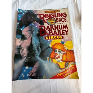 Peut inclure: Une affiche vintage du cirque Ringling Bros. et Barnum & Bailey. L'affiche présente un rhinocéros, une panthère noire et un clown. Le texte comprend "120th Anniversary Edition".