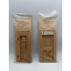 May include: Two unfinished light-colored wooden dollhouse doors packaged in clear plastic bags. The left door features a multi-pane window design, while the right door has a solid panel with a cross-brace detail and a small rectangular window.