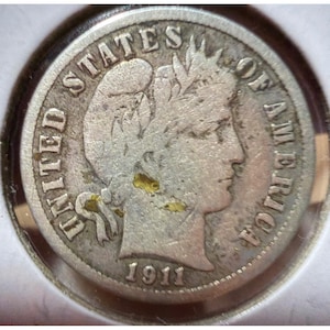 Op de afbeelding: Een zilveren munt uit 1911 met de inscriptie "UNITED STATES OF AMERICA". De munt toont een vrouwenprofiel en zit in een beschermende behuizing.