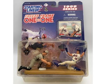 May include: A Starting Lineup 1999 Series Freeze Frame One on One baseball collectible set in original packaging. The set includes two plastic baseball player figures in action poses, a trading card, and a display base, all encased in clear plastic.