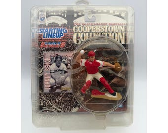 May include: A Starting Lineup Cooperstown Collection 1997 Series action figure of Johnny Bench in a red and white baseball uniform, packaged in a clear plastic blister card with a printed stadium background and player portrait.