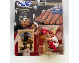 May include: A Starting Lineup Johnny Bench baseball action figure in a crouched catcher position, wearing a white uniform with red accents and a red mask. The packaging includes a collector card and a graphic of a baseball glove and ball.