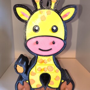 Puede incluir: Una figura de jirafa impresa en 3D con contorno negro, cara y cuerpo de color amarillo brillante, hocico rosa y manchas naranjas. La jirafa tiene ojos negros con pupilas blancas, cuernos pequeños y pezuñas marrones. El diseño es plano.