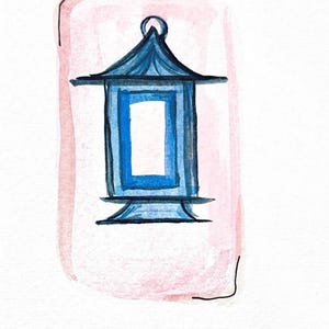 May include: Watercolor illustration of a blue pagoda-style lantern with a rectangular opening, set against a soft pink background. The lantern has a detailed roof and base, with a small loop at the top. The artwork is signed in the bottom right corner.
