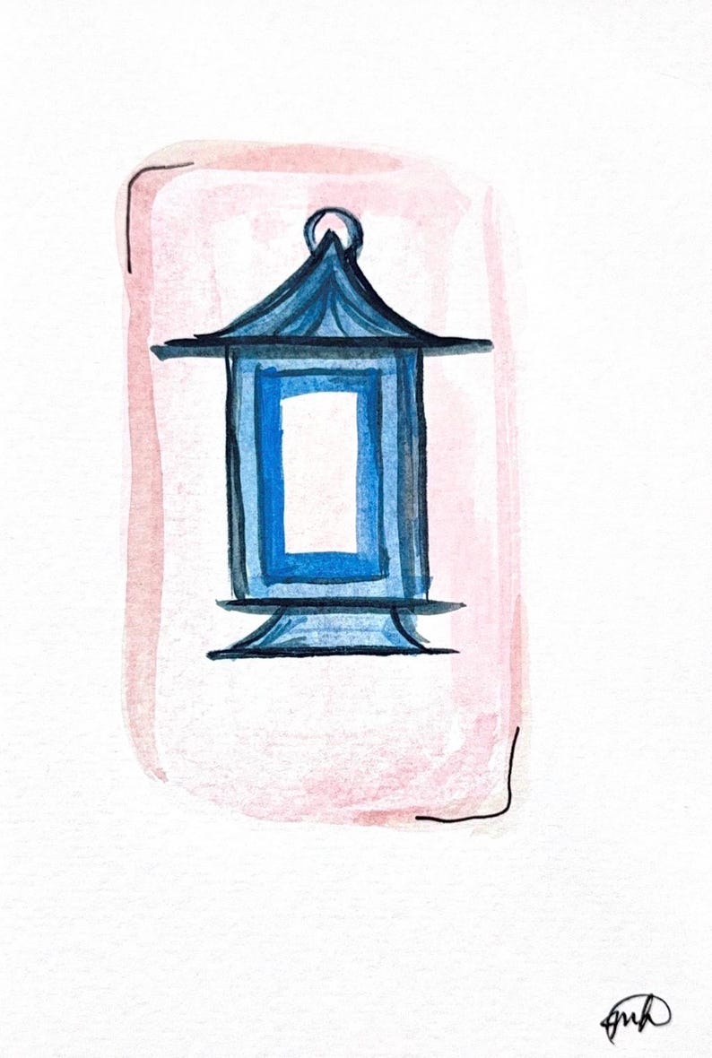 May include: Watercolor illustration of a blue pagoda-style lantern with a rectangular opening, set against a soft pink background. The lantern has a detailed roof and base, with a small loop at the top. The artwork is signed in the bottom right corner.