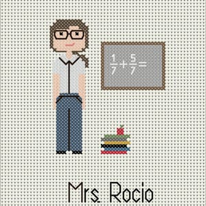 May include: A cross-stitch pattern on white fabric featuring a person with brown hair and glasses, a gray chalkboard with the math equation 1/7 + 5/7 =, a stack of colorful books topped with a red apple, and the text Mrs. Rocio at the bottom.