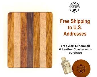 May include: A rectangular cutting board made of vertical strips of light, medium, and dark brown wood. Beside it is a small clear bottle labeled 2 oz. Mineral Oil and a round brown leather coaster with the Reinvented Boards logo.