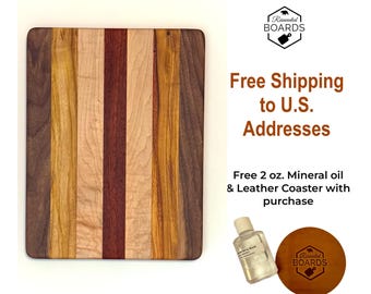 May include: A rectangular cutting board constructed from vertical strips of wood in varying shades of dark brown, light tan, and reddish-brown. Included is a small clear bottle of mineral oil and a round brown leather coaster with a logo.
