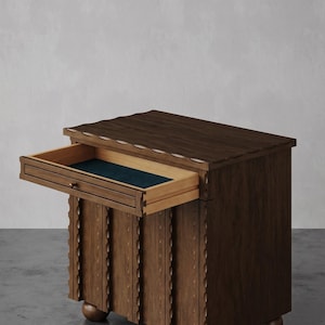 Puede incluir: Un mueble de madera oscura con un cajón abierto que revela un interior verde azulado. El mueble tiene un diseño tallado decorativo y descansa sobre pies redondeados. El borde superior del mueble tiene un diseño festoneado.