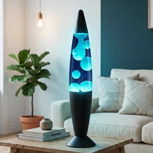 May include: A black lava lamp with a conical top and base, and a clear glass container filled with blue liquid and floating blue blobs. The lamp is on a wooden table, with a plant and books in the background. The lamp is approximately 18 inches tall.