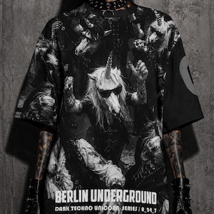 May include: Black graphic t-shirt featuring a dark techno unicorn design. The shirt has the text "BERLIN UNDERGROUND DARK TECHNO UNICORN SERIES / 0_24_7" printed on the front. The design is in shades of black and white.